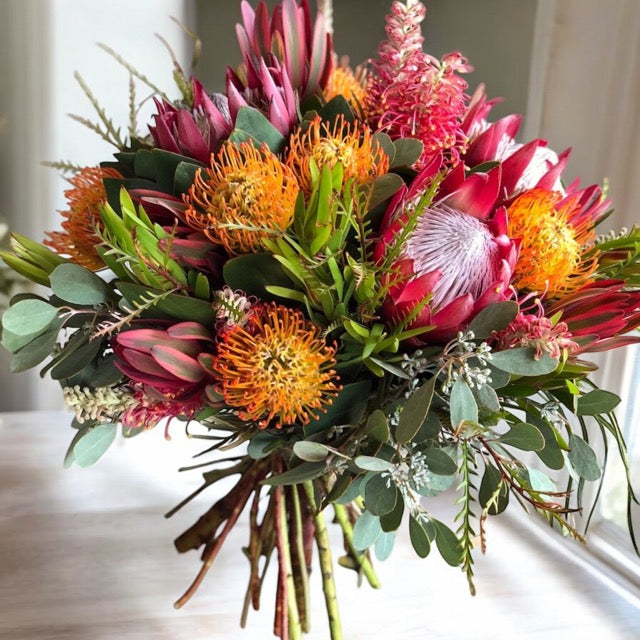 Bouquet autunnale con protee, nutans, leucadendron e verde decorativo.